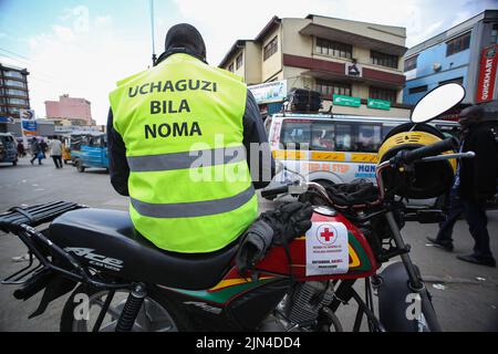 Nairobi, Kenia. 08. August 2022. Ein Boda Boda (Motorrad) Fahrer in einer reflektierenden Jacke mit dem Slogan "Uchaguzi bila noma" (Wahlen ohne Gewalt). Dies ist Teil einer Friedenskampagne, die vom Roten Kreuz Kenias in Nairobi durchgeführt wird. Die Kenianer werden am 9.. August 2022 abstimmen, und die unabhängige Wahl- und Grenzkommission (IEBC) schließt ihre Vorbereitungen für die Durchführung der Parlamentswahlen weiter ab. Kredit: SOPA Images Limited/Alamy Live Nachrichten Stockfoto