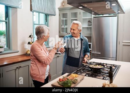 Ein Paar, das beim Kochen in der Küche einen Toast macht. Stockfoto