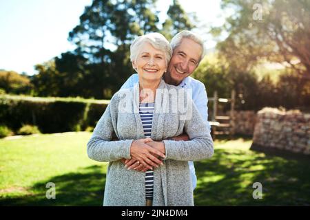 Unser Leben glücklich immer nach. Porträt eines liebevollen Seniorenpaares, das zu Hause in ihrem Hinterhof posiert. Stockfoto