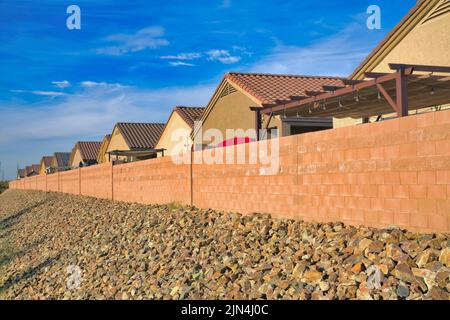 Außerhalb eines Wohngebiets mit Betonzaun in Tucson, Arizona. Es gibt Felsen an der Vorderseite in der Nähe der Betonmauer gegen die Häuser am Stockfoto