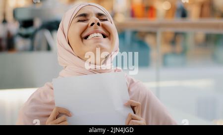 Nahaufnahme junge aufgeregt glücklich arabische Frau in Hijab erhalten Brief lesen gute unglaubliche Nachrichten lächelnd ausgezeichnete medizinische Testergebnisse genehmigen für neue Stockfoto