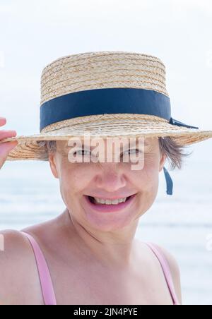Porträt einer glücklichen grauhaarigen Frau, die den Rand ihres Bootes aus der Meeresbrise mit der Hand stützt und die Kamera anlächelt. Konzept des Glücks. Stockfoto