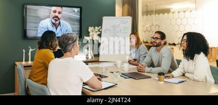 Multikulturelle Geschäftsleute, die eine Videokonferenz in einem Sitzungssaal abhalten. Gruppe innovativer Business Professionals, die kreative Ideen während der Arbeit austauschen Stockfoto