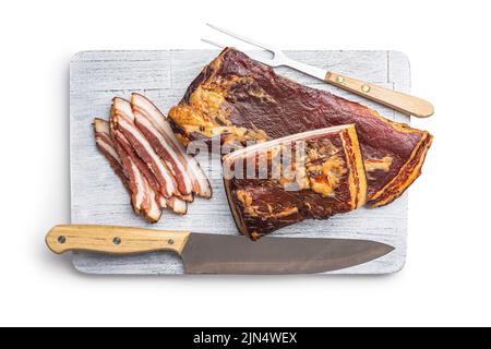 Geräucherter Speck in Scheiben auf Schneidebrett isoliert auf weißem Hintergrund. Stockfoto