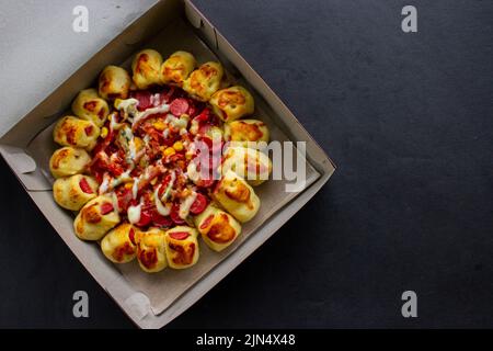 Leckere Pizza mit Pilzauflage, Mais, Hühnerwurst, Speck, Mayonnaise, Grillsauce, Tomate, Chili auf schwarzem Hintergrund. Stockfoto