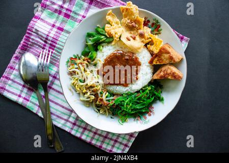 Nasi Pecel oder sego Pecel ist ein traditionelles javanesisches Reisgericht aus gedünstetem Reis mit Gemüsesalat, Erdnusssauce, Tempeh, Tofu-Bohnensprossen und Crackern Stockfoto