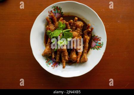 Würzige Hähnchenfüße mit Sellerie, Chili, Zwiebel, Knoblauch, serviert mit einem weißen Teller auf dem Tisch Stockfoto