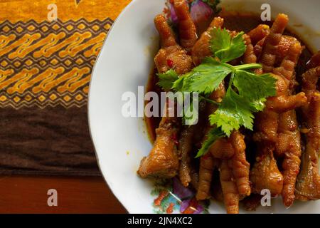 Würzige Hähnchenfüße mit Sellerie, Chili, Zwiebel, Knoblauch, serviert mit einem weißen Teller auf dem Tisch Stockfoto