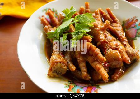 Würzige Hähnchenfüße mit Sellerie, Chili, Zwiebel, Knoblauch, serviert mit einem weißen Teller auf dem Tisch Stockfoto