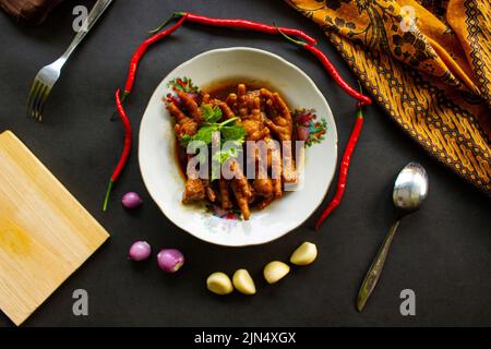 Würzige Hähnchenfüße mit Sellerie, Chili, Zwiebel, Knoblauch, serviert mit einem weißen Teller auf dem Tisch Stockfoto