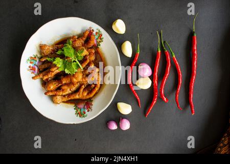 Würzige Hähnchenfüße mit Sellerie, Chili, Zwiebel, Knoblauch, serviert mit einem weißen Teller auf dem Tisch Stockfoto