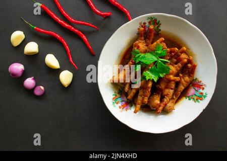 Würzige Hähnchenfüße mit Sellerie, Chili, Zwiebel, Knoblauch, serviert mit einem weißen Teller auf dem Tisch Stockfoto