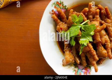 Würzige Hähnchenfüße mit Sellerie, Chili, Zwiebel, Knoblauch, serviert mit einem weißen Teller auf dem Tisch Stockfoto