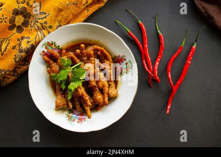 Würzige Hähnchenfüße mit Sellerie, Chili, Zwiebel, Knoblauch, serviert mit einem weißen Teller auf dem Tisch Stockfoto
