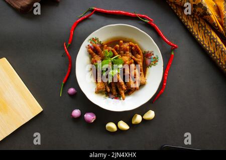 Würzige Hähnchenfüße mit Sellerie, Chili, Zwiebel, Knoblauch, serviert mit einem weißen Teller auf dem Tisch Stockfoto