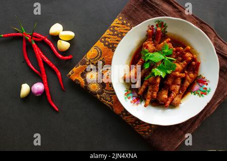 Würzige Hähnchenfüße mit Sellerie, Chili, Zwiebel, Knoblauch, serviert mit einem weißen Teller auf dem Tisch Stockfoto