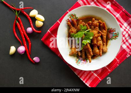 Würzige Hähnchenfüße mit Sellerie, Chili, Zwiebel, Knoblauch, serviert mit einem weißen Teller auf dem Tisch Stockfoto