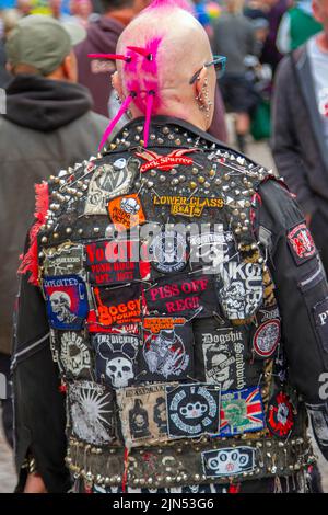 Dekorierte Jacken mit Nieten, T-Shirts, Anti-Establishment- und exzentrische Slogans. Lederjacken mit Bandnamen beim Rebellion Music Event, dem weltweit größten Punk-Festival in Blackpool. Anfang August finden in den Wintergärten von Blackpool zahlreiche Punk-Bands für das Rebellion Festival 21. statt, das Tausende von Touristen anzieht. Jeden August kommen in Blackpool über 4 Tage lang die Besten von Punk zu diesem gesellschaftlichen Ereignis des Jahres zusammen, mit 4 Tagen Musik auf 6 Bühnen mit Massen von Bands. Stockfoto