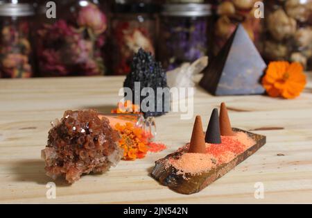 Aragonitkristall mit Weihrauch und Steinpyramide auf Meditationstisch Stockfoto