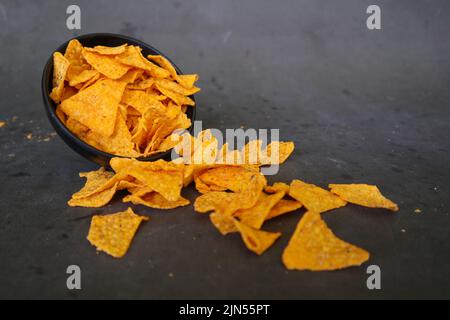 „Tortilla Chip ist Maischips oder Call Nachos, serviert in einer Schüssel, auf schwarzem Hintergrund aus Mais“ Stockfoto