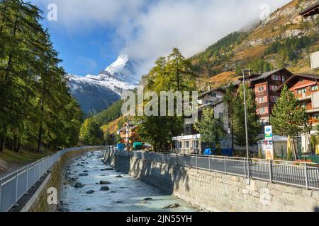 Zermatt, Schweiz - 7. Oktober 2019: Blick auf die Straße der Stadt im berühmten Skigebiet Schweizer Alpen, Fluss, Matterhorn Schneegipfel Stockfoto