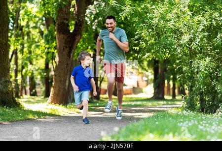 Glücklicher Vater und Sohn wetteifern beim Laufen im Park Stockfoto