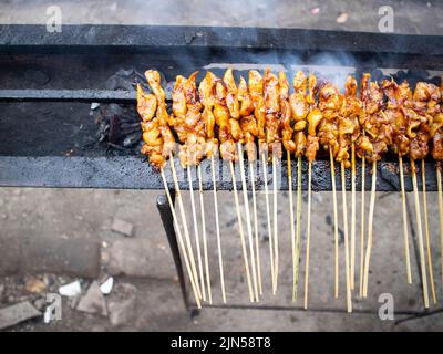 Sate Ayam oder Chicken Satay, Chicken Satay auf dem Grillplatz mit Rauch von Menschen mit lecker aussehenden, traditionellen Satay aus java, Madura platziert. Stockfoto