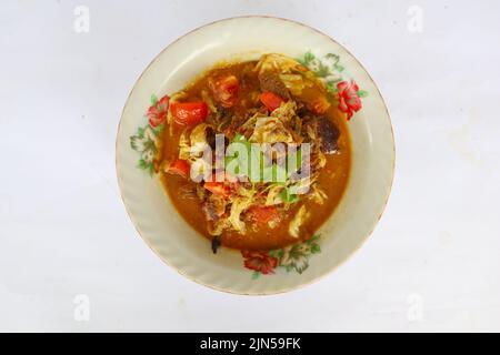 'Goat Curry oder Gulai Kambing, Lebensmittel aus asien. Köstliches Ziegenfleisch-Curry, serviert in einem bowl.served mit Tomaten, Gewürzen, Sellerie und Kohl Stockfoto