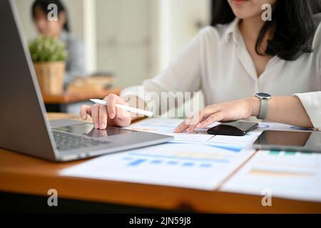 Eine erfolgreiche Geschäftsfrau oder Finanzanalytikerin, die an ihrem Schreibtisch arbeitet und mit einem Laptop Finanzdaten analysiert. Zugeschnittenes Bild Stockfoto