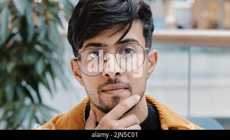 Kopfschuss junger nachdenklicher indischer Mann, der Hand am Kinn hält Denken tief in Gedanken auf der Suche entscheidet, findet Lösung des Problems schwierig Stockfoto