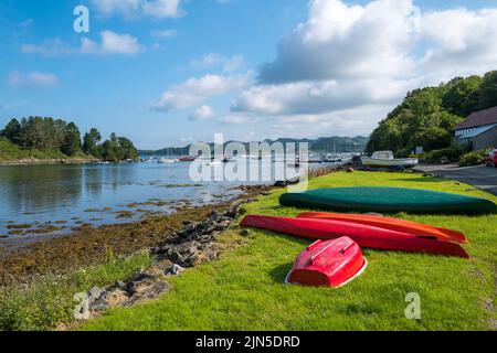 Kajaks warten auf der loch-Seite am Crinan Harbour Argyll Scotland in der Nähe des Hafens und den festverankerten Booten im Meer Stockfoto