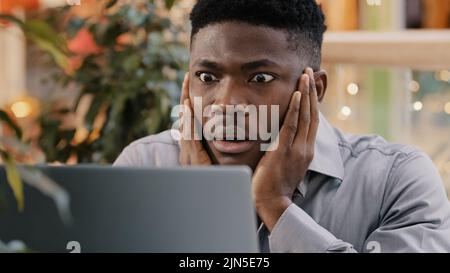 Nahaufnahme junger Geschäftsmann Blick auf Laptop-Bildschirm immer schlechte Nachrichten überrascht schockiert Mann, der Kopf gefunden Fehler in elektronischer Stockfoto