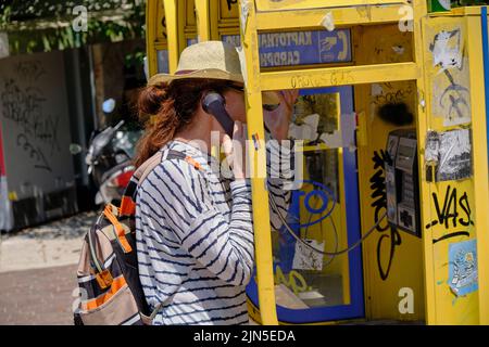 Frau, die im Zentrum von Athen ein öffentliches Telefon benutzt Stockfoto