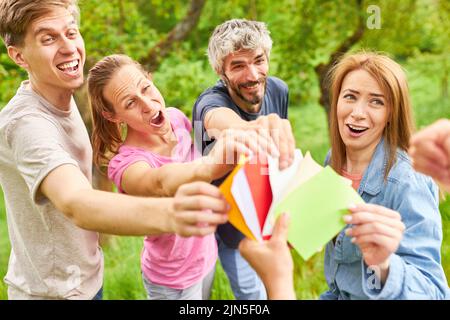 Fröhliche Gruppe von jungen Menschen haben Spaß beim Teambuilding-Spiel und ziehen bunte Karten Stockfoto