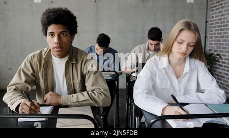 Diverse junge Gruppe Menschen Klassenkameraden sitzen im Klassenzimmer bei der Vorlesung schriftlich Notiz in Notebook-Studenten, die Prüfung schreiben Test junge kaukasische Mädchen Stockfoto