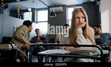 Traurig frustriert unsicher Mädchen Studentin sitzen im Klassenzimmer am Schreibtisch leiden unter Missbrauch schlechte Haltung Spott von Klassenkameraden junge Frau Gefühl Stockfoto