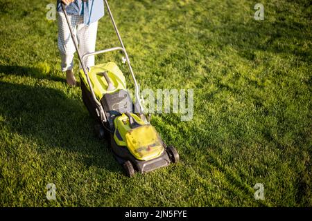 Mann mäht den Rasen mit Rasenmäher im Hinterhof Stockfoto