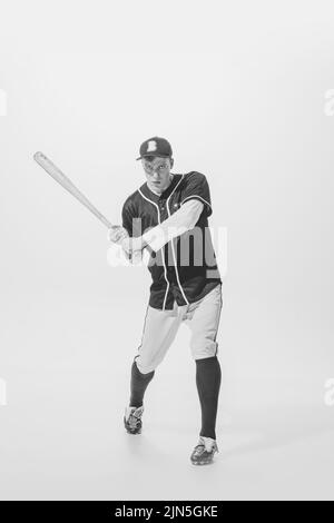 Portrait von jungen Mann, Baseballspieler, Teig bereit, Ball mit Fledermaus zu schlagen. Schwarzweiß-Fotografie. Konzentration und Motivation Stockfoto