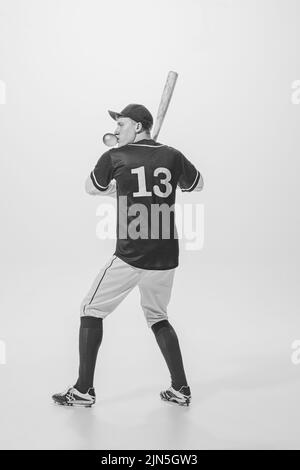 Porträt eines jungen Mannes, Baseballspieler, der mit Bubblegum spielt, bereit, den Ball mit dem Schläger zu schlagen. Schwarzweiß-Fotografie Stockfoto