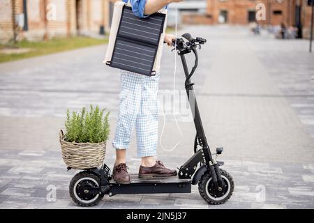 Stilvoller Kerl fährt Elektroroller und nutzt Handy unterwegs Stockfoto