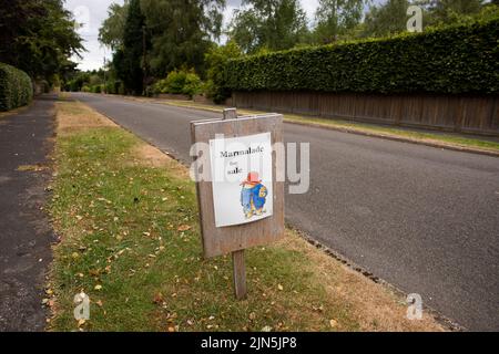 Ein selbstgemachtes „Marmalade for Sale“-Schild mit einem Bild von Paddington Bear auf einem Grasrand einer Straße in High Kelling, Norfolk. Stockfoto