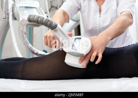 Die Frau erhält eine Flüssiggasmassage, um Cellulite aus ihrem Körper zu entfernen und die Beine zu heben. Konzept-Beauty-Therapie im Spa-Salon. Stockfoto