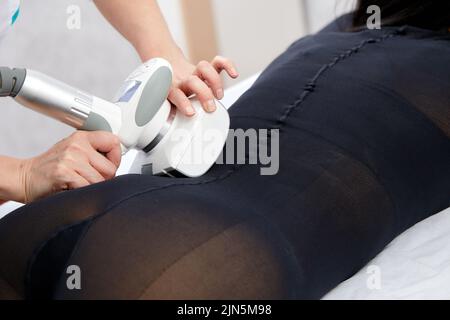 Die Frau erhält eine Flüssiggasmassage, um Cellulite aus ihrem Körper zu entfernen und die Beine zu heben. Konzept-Beauty-Therapie im Spa-Salon. Stockfoto