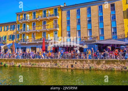 MAILAND, ITALIEN - 9. APRIL 2022: Die laute, überfüllte Außenterrasse des kleinen Restaurants am Naviglio Grande Canal, am 9. April in Mailand Stockfoto