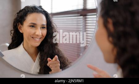 Junge glückliche selbstbewusste Frau, die im Badezimmer steht und im Spiegel schaut, probt Rede anweist, sich auf ein Interview vorzubereiten, sagt inspirierende Worte motiviert Stockfoto