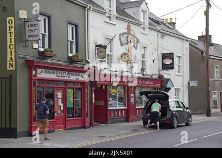 Ein Mann lädt ein Auto vor dem Castle Off License, einem ehemaligen traditionellen irischen Pub, in Tralee, County Kerry, Irland Stockfoto