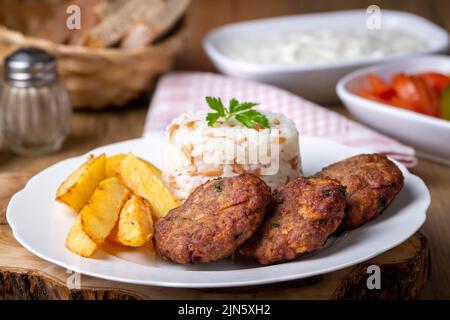 Traditionelle türkische Küche; trockene Fleischbällchen oder Inegöl-Fleischbällchen mit Kartoffeln und Reis pilav (türkischer Name; Kuru kofte) Stockfoto
