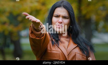 Junge frustrierte hispanische Frau zeigt mit Handfläche Richtung Kamera sagt hey Sie eindringlich rufen verzweifelt emotional verärgert Mädchen steht im Freien Stockfoto