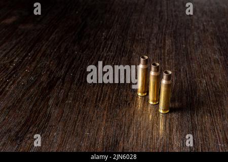 Eine Nahaufnahme von drei leeren Geschossgehäusen auf einem dunklen Holztisch Stockfoto