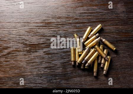 Eine Nahaufnahme leerer Geschosshüllen auf einem dunklen Holztisch Stockfoto
